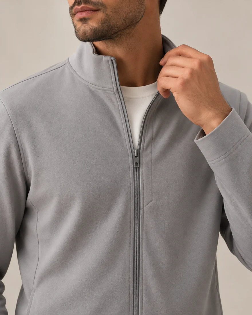 Close-up of the Zip Jacket: a stand collar and a full front zip being pulled up
